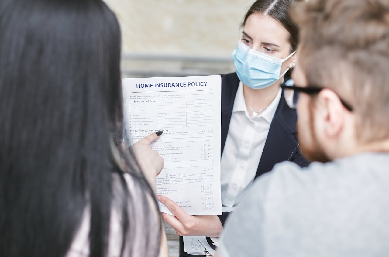 A professional woman explains a home insurance policy to clients during a meeting. Indoors setting.